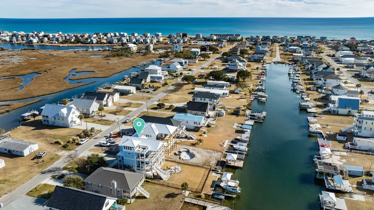 A sweeping view capturing the intersection of canal, ocean, and houses, with boats moored along the waterways. The image showcases the proximity of the home to both the canal and the Atlantic, highlighting the coastal lifestyle and easy access to water-based exploration and community life.