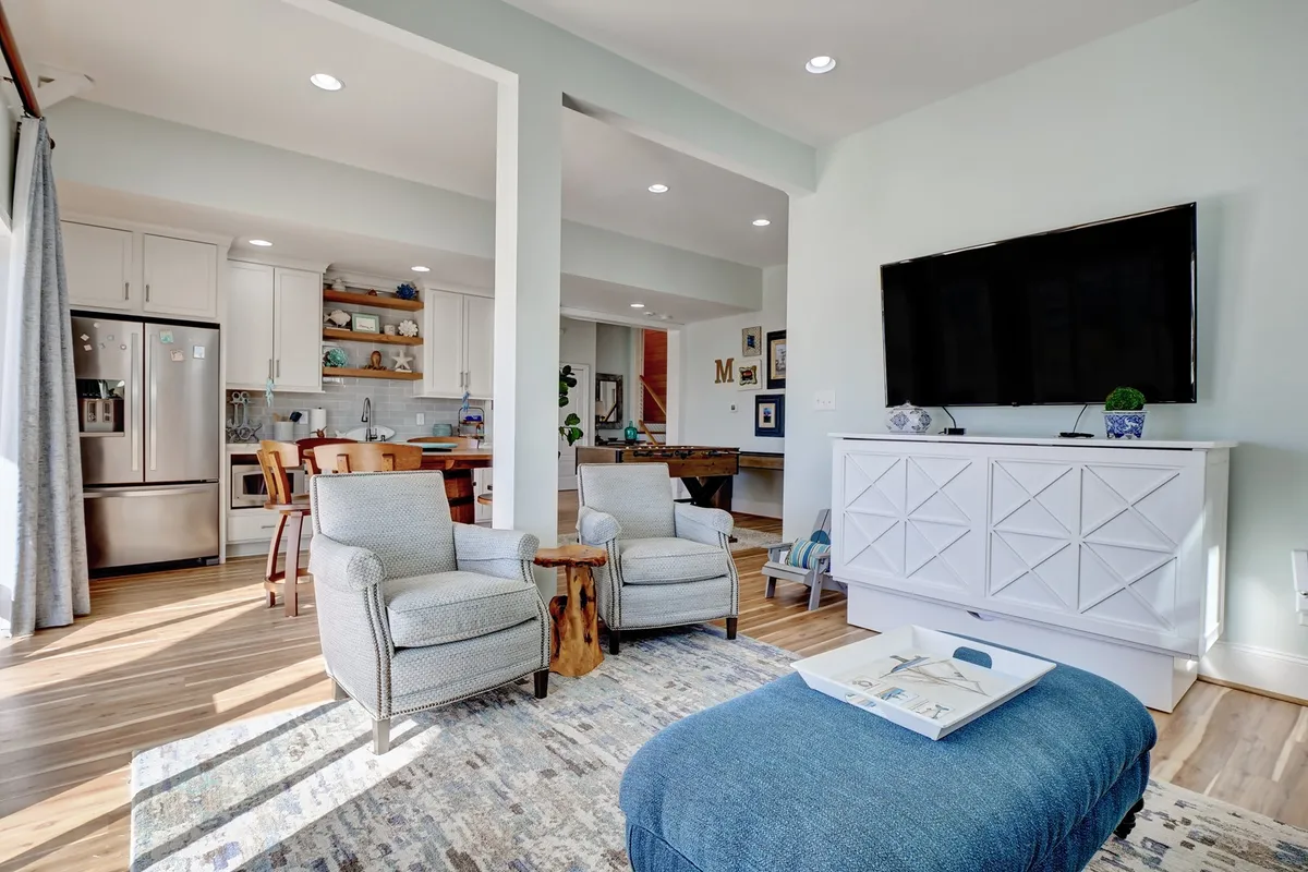 A cozy lounge space is depicted here, complete with comfortable chairs, a coffee table, a television, and an adjacent kitchen area. The setup is ideal for watching movies, relaxing, and sharing snacks—key elements for both casual family meals and festive gatherings.