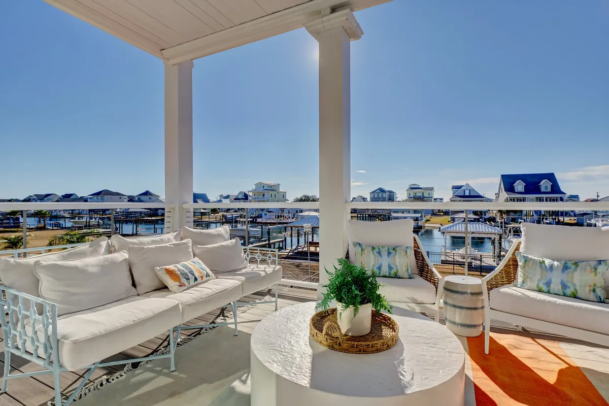 A tranquil outdoor seating area overlooks a marina, with plush pillows and greenery creating an inviting atmosphere. Friends and family can relax with coffee or cocktails while enjoying panoramic water views and the glow of sunset. The space is both intimate and open, ideal for smaller gatherings or quiet retreats during larger events.