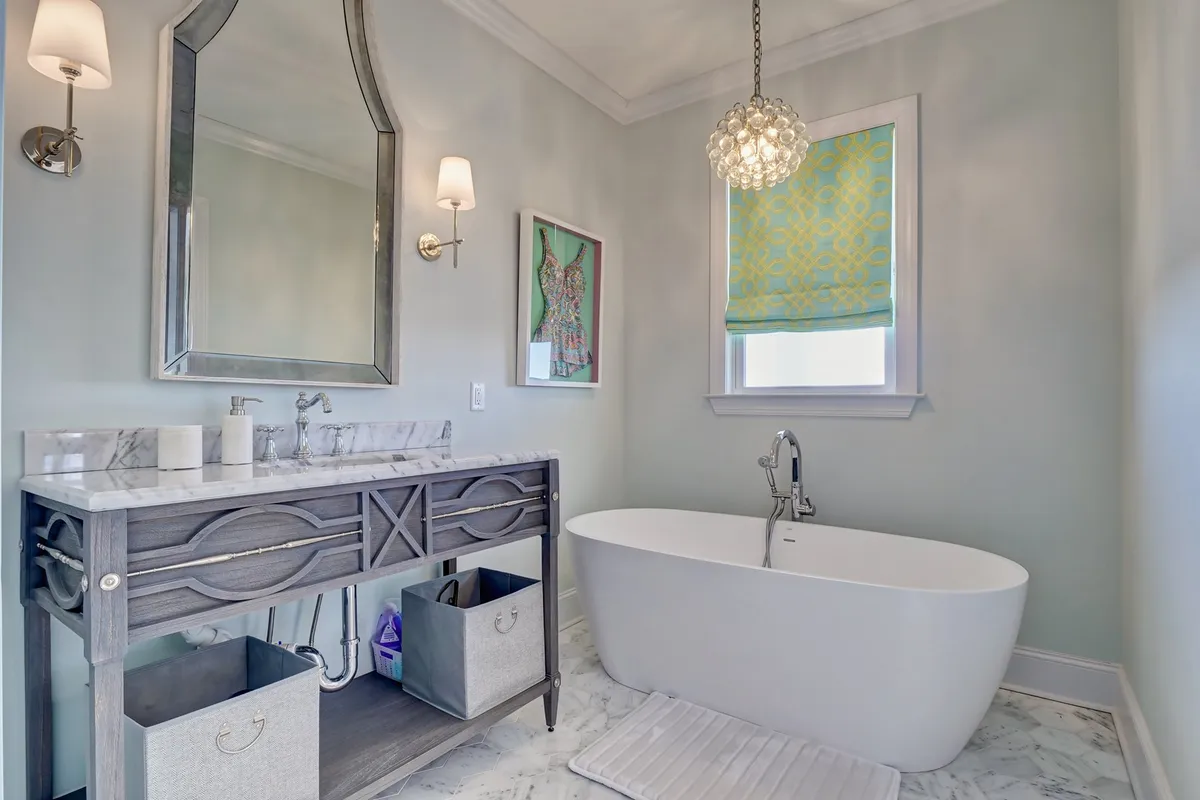 A spa-like bathroom boasting a freestanding bathtub, a marble-topped vanity, a decorative mirror, and vibrant window treatments. The room balances luxury and personality, evoking a sense of rejuvenation and pampering.