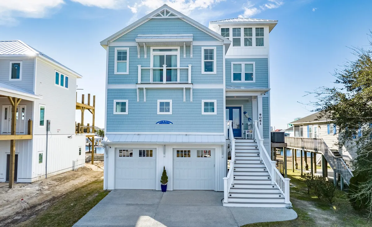 A cheerful exterior view of a blue house with a large front porch and multiple balconies, surrounded by a lawn and well-maintained landscaping. There’s ample space for outdoor games and socializing, and the home’s welcoming design hints at multi-generational gatherings.